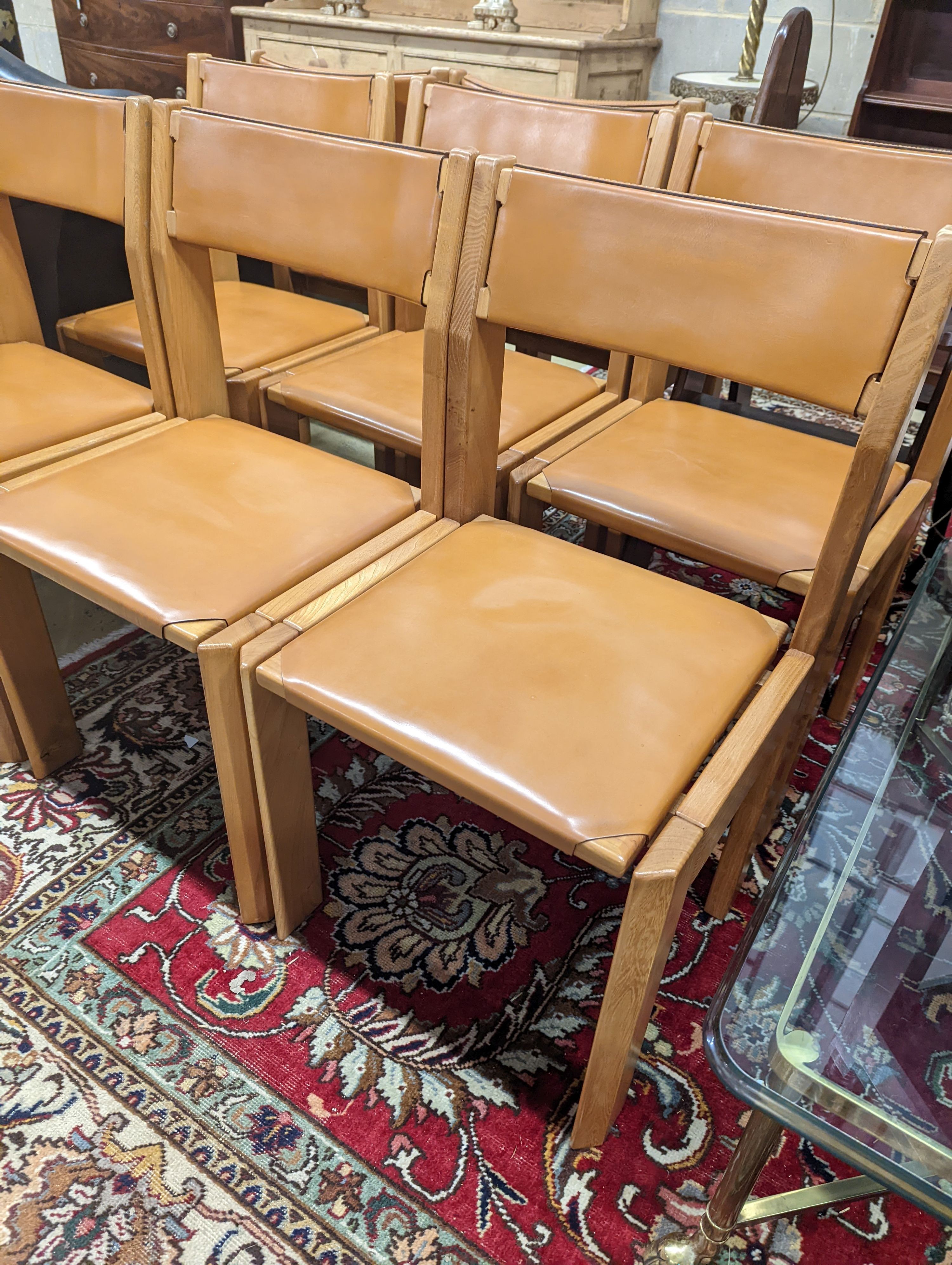 A set of eight mid century design walnut and tan leather dining chairs, width 48cm, depth 44cm, height 84cm